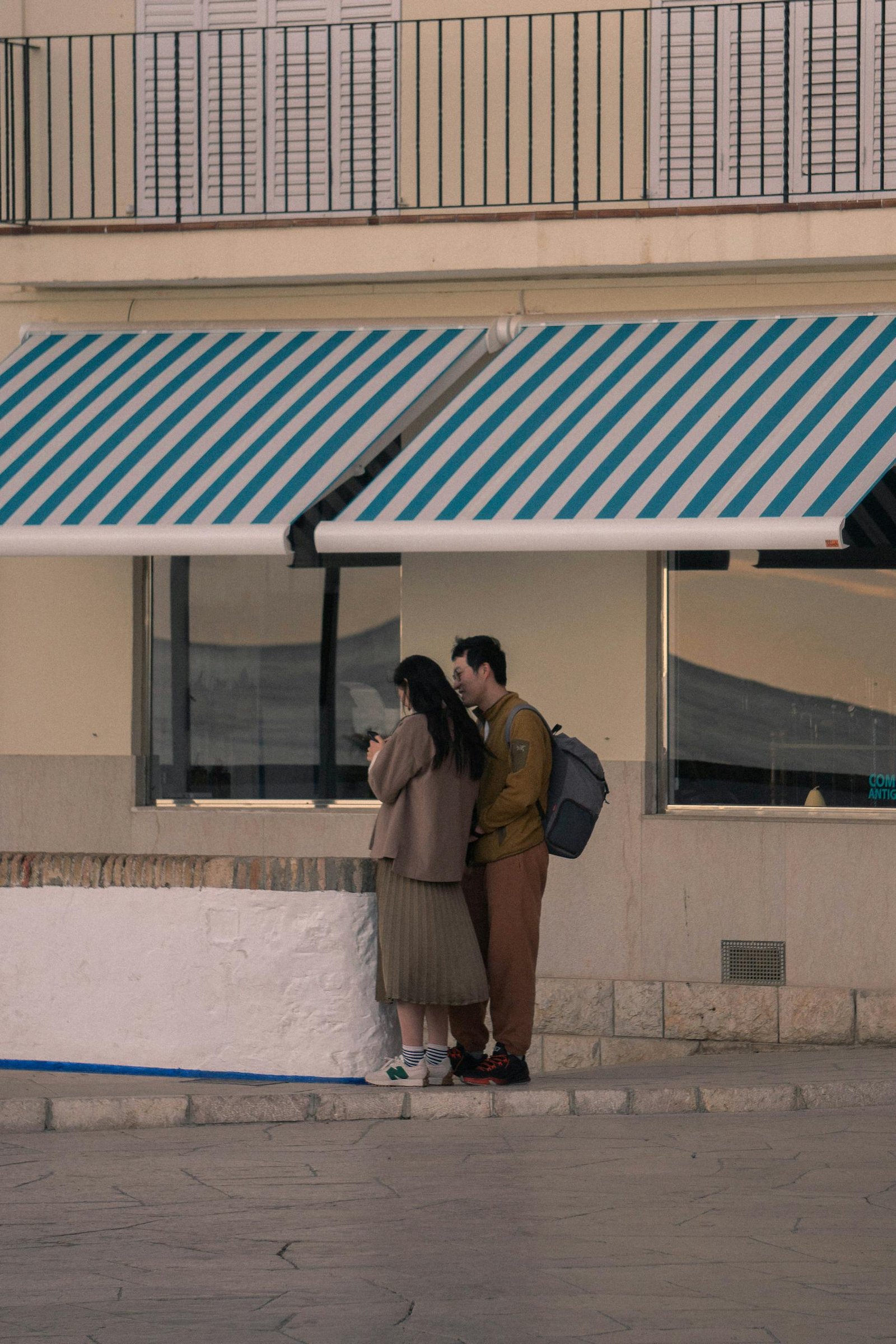 A couple stands near a shop in Sitges, Spain, capturing the urban feel.
