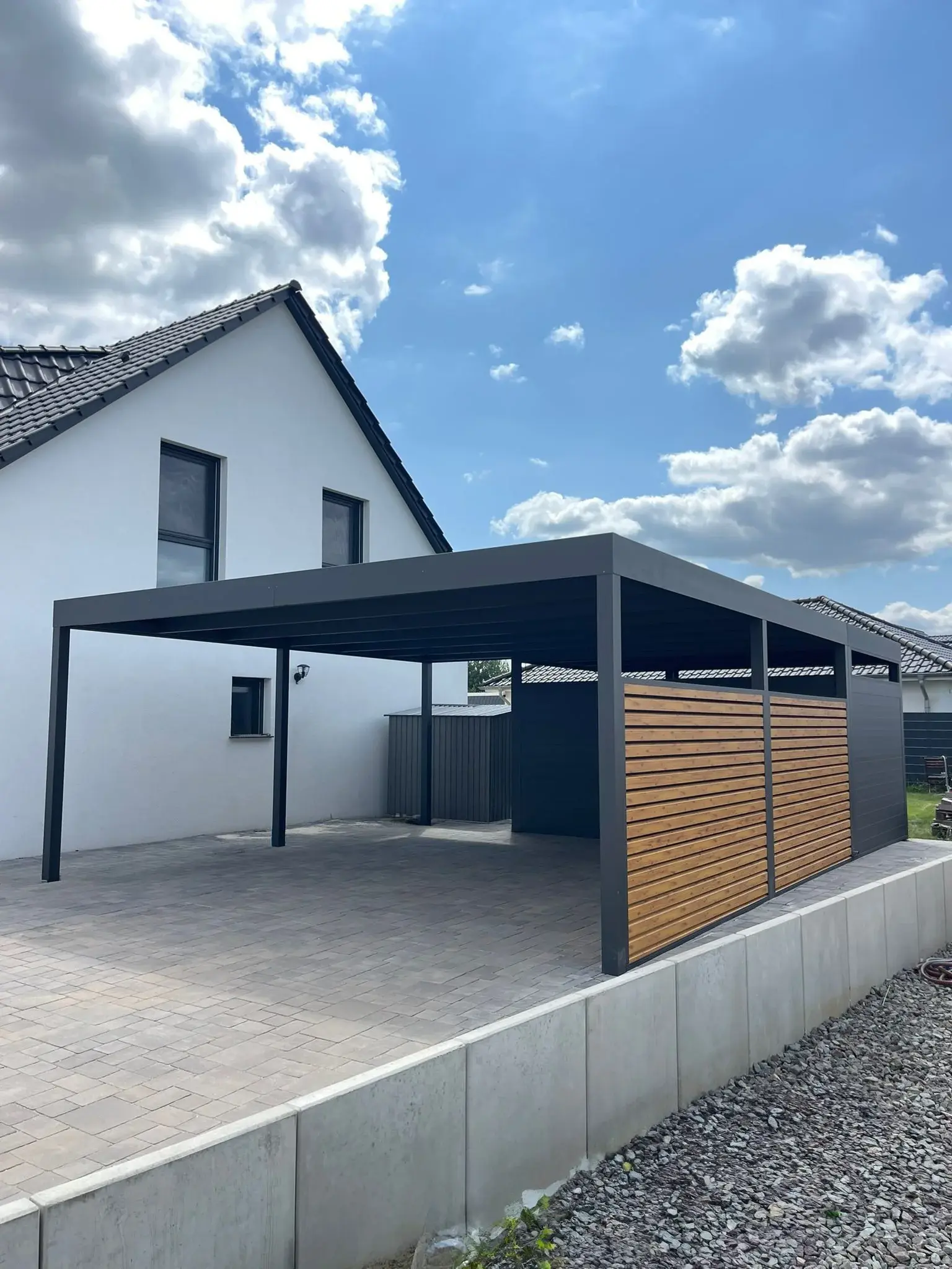 Anthrazitfarbener Doppelcarport mit Flachdach und seitlichem Sichtschutz aus Holzlamellen, Referenzprojekt in Köln und Leverkusen