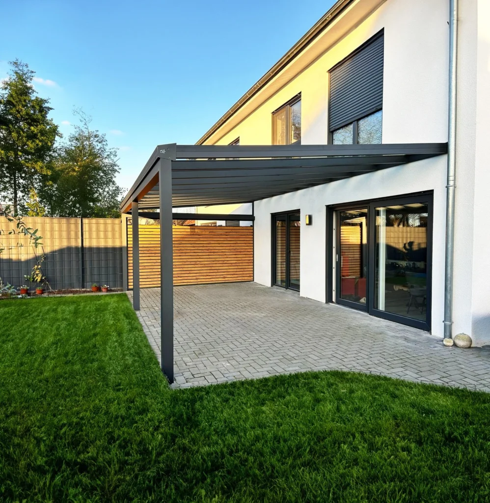 Moderne Terrassenüberdachung aus anthrazitfarbenem Aluminium mit integriertem Holz-Sichtschutz an einem Einfamilienhaus in Bergisch Gladbach