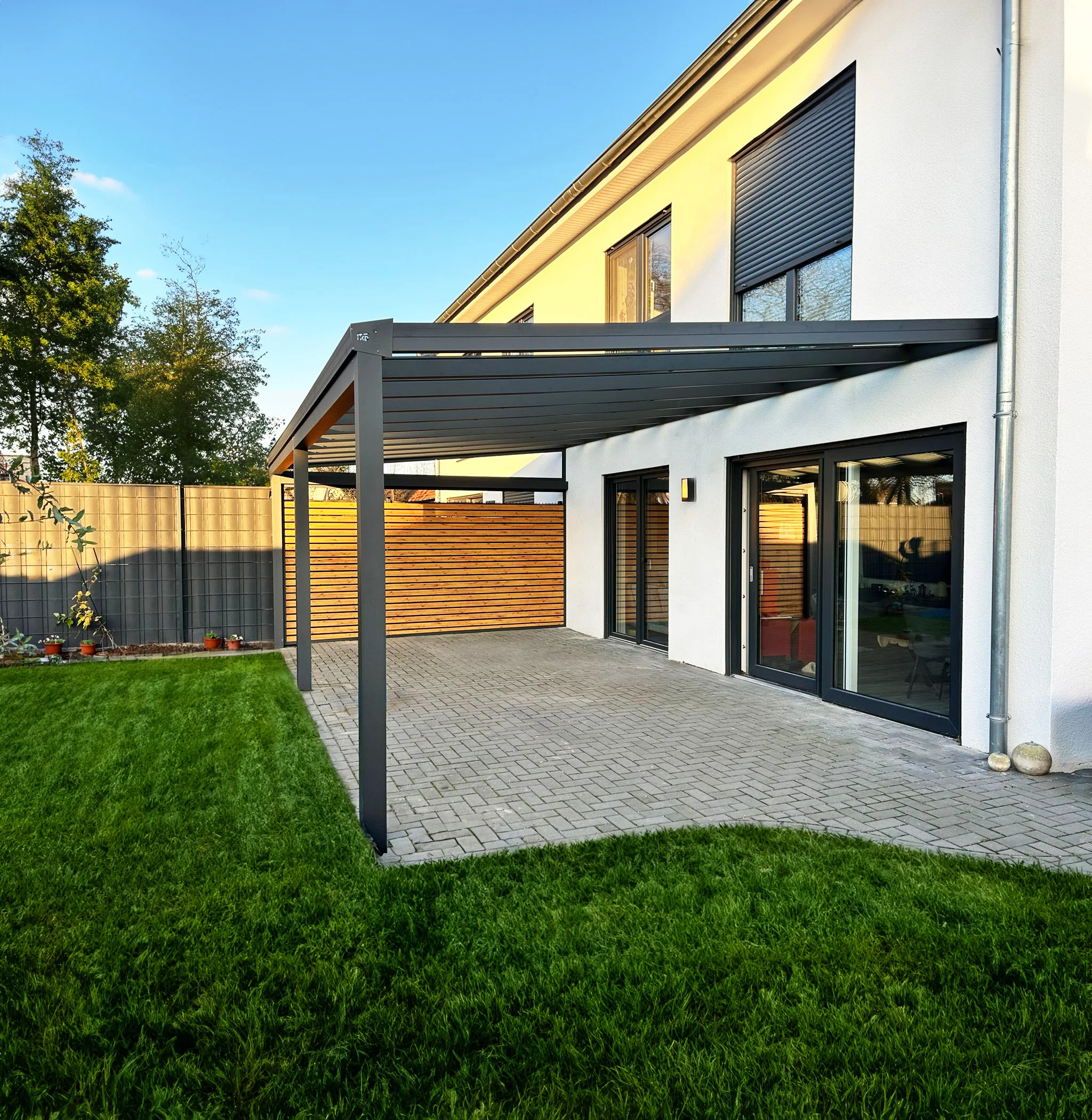 Aluminium-Terrassenüberdachung in Anthrazit am weißen Haus mit Rasen in Leverkusen
