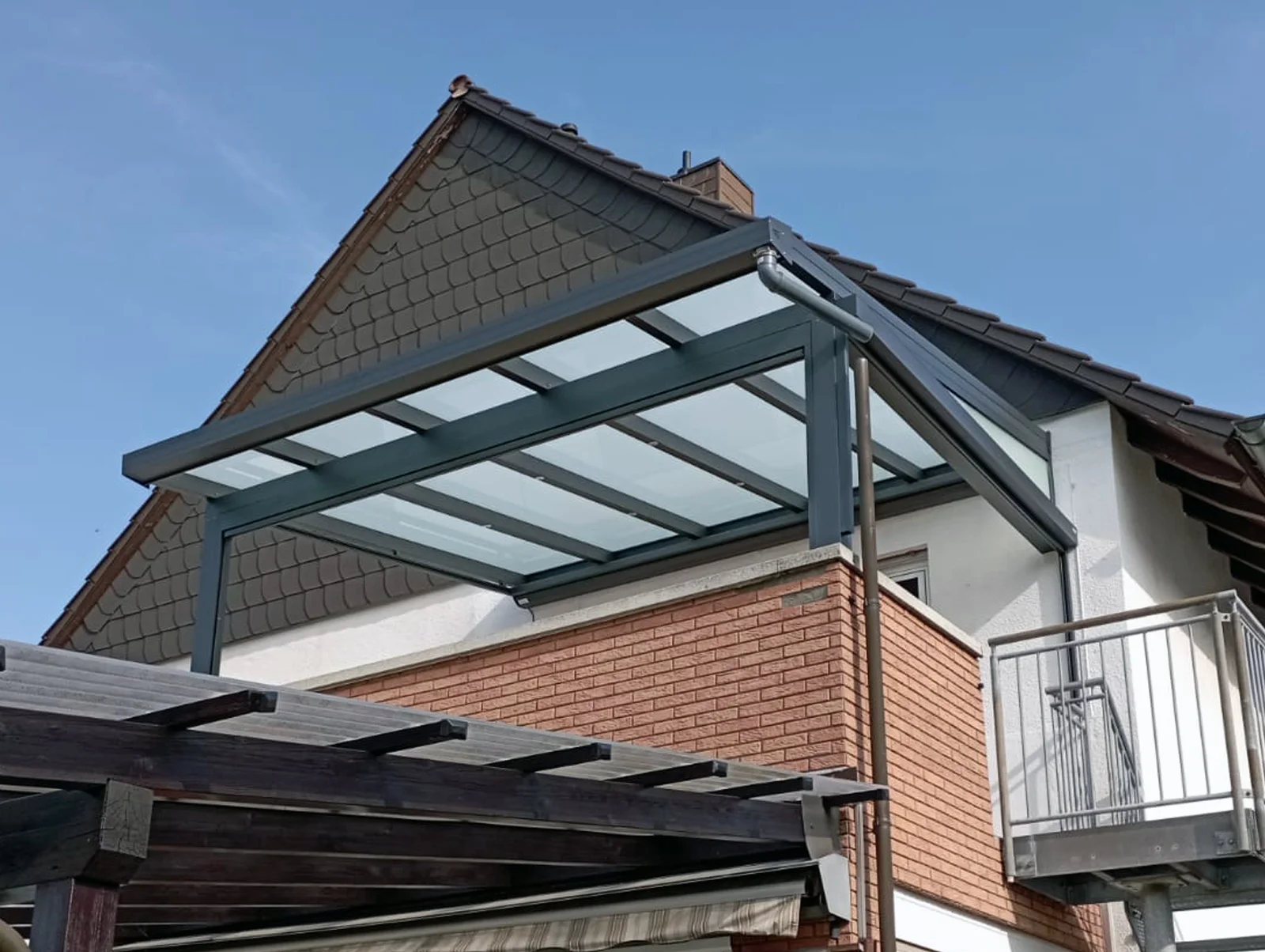 Balkonüberdachung an einem Einfamilienhaus in Anthrazit mit Glasdach unter Satteldach