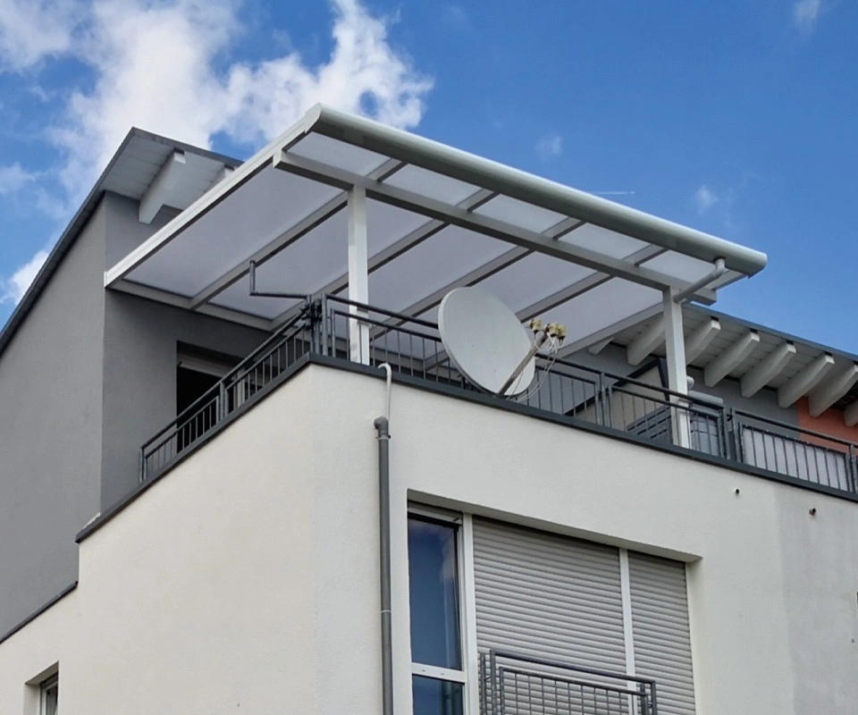 Weiße Balkonüberdachung mit Glasdach an einem Mehrfamilienhaus
