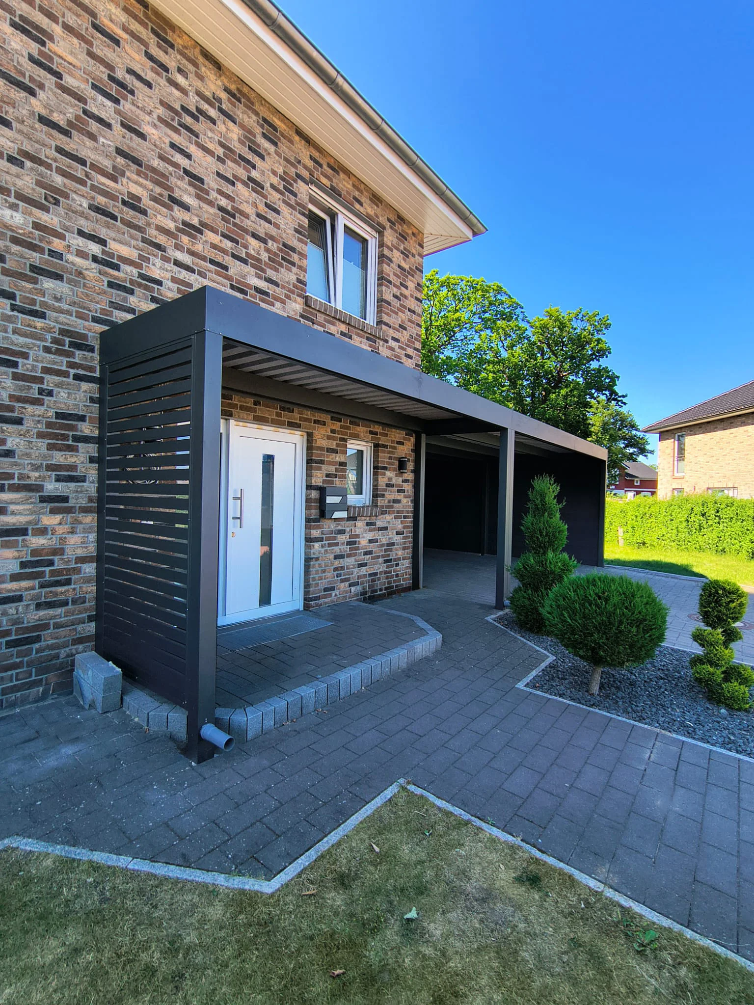 Moderner Aluminium-Carport in Anthrazit an einer Natursteinfassade in Leverkusen