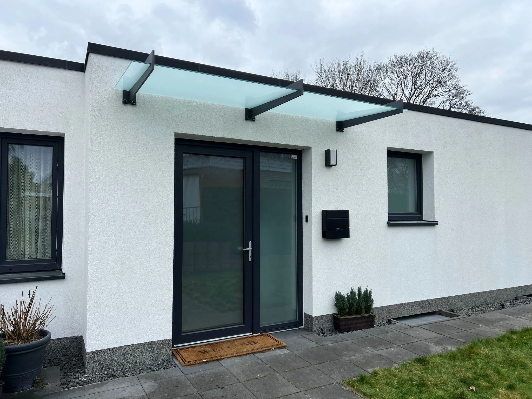 Breites Milchglas-Vordach an einem Bungalow in Köln