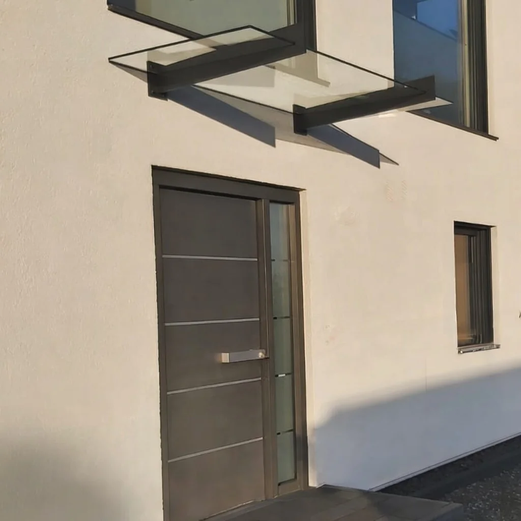 Glasvordach mit Wandhalter an einem modernen Eingangstor in Burscheid