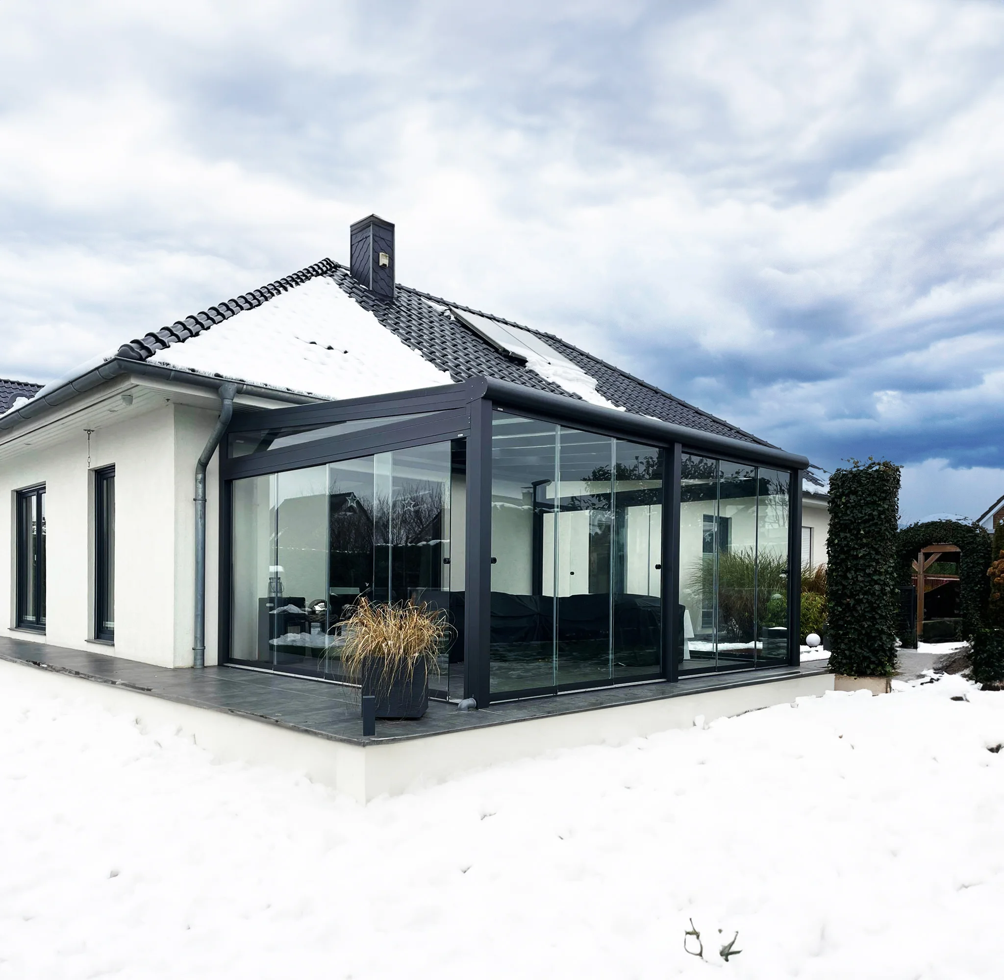 Kaltwintergarten aus Aluminium mit Glasschiebewänden im Winter mit Schnee in Langenfeld