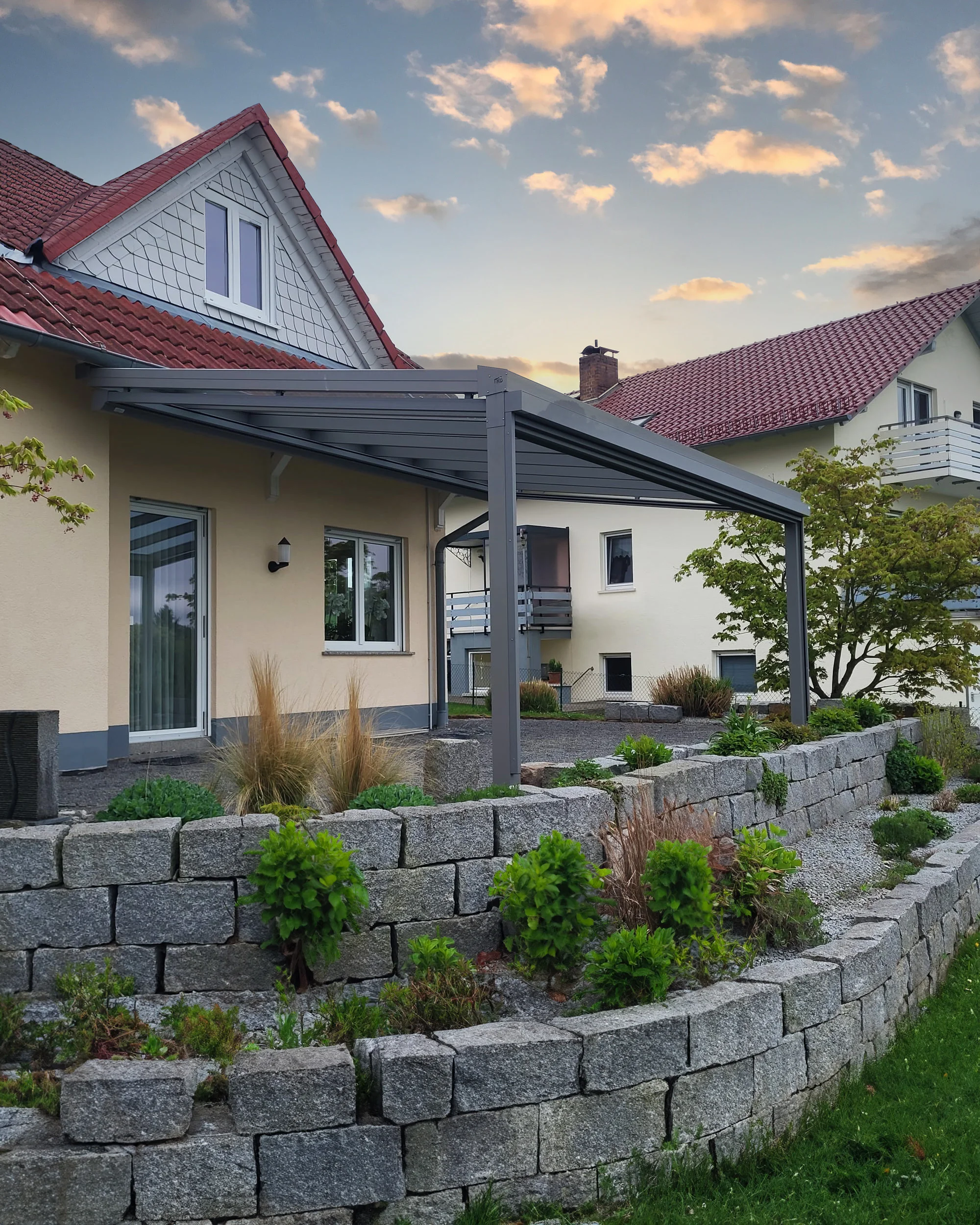 Aluminium-Terrassenüberdachung in Anthrazit an einer Natursteinmauer im Garten in Leverkusen