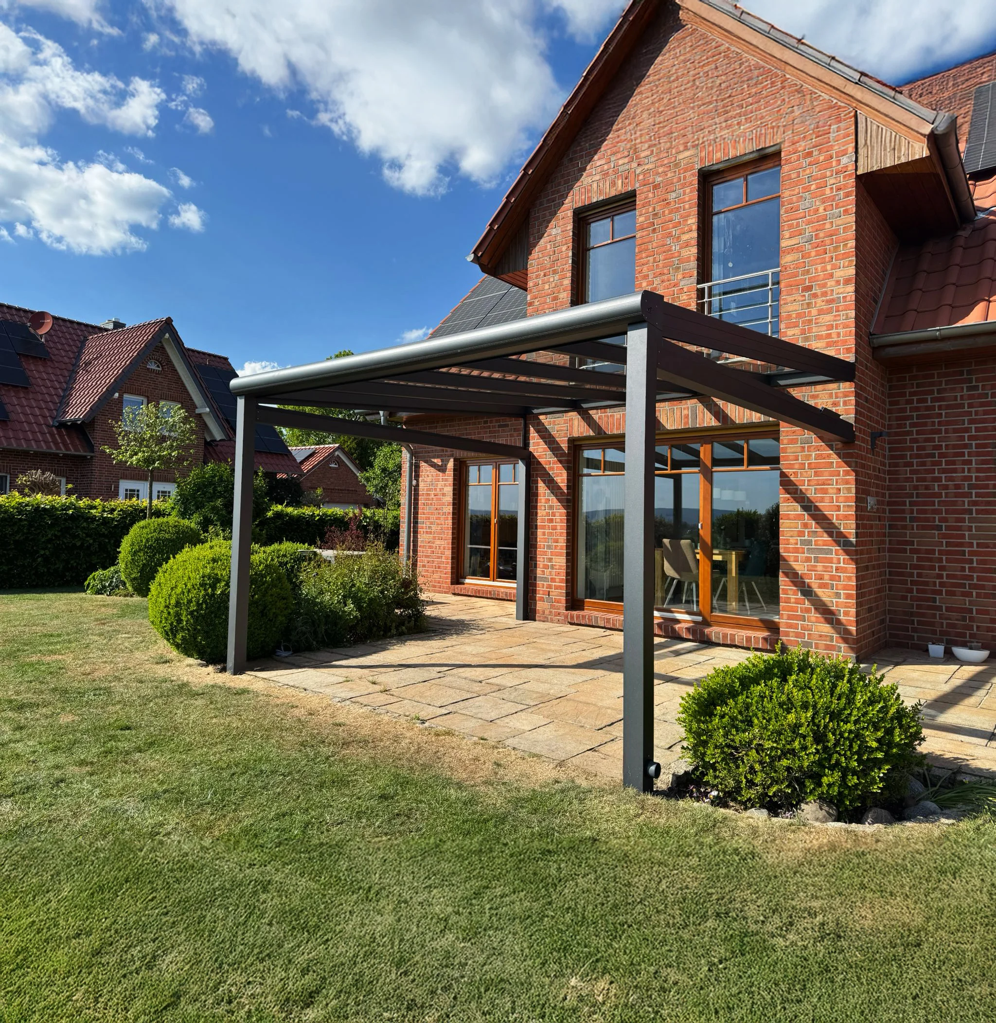 Terrassenüberdachung mit festem Glasdach aus Aluminium am Klinkerhaus in Leverkusen
